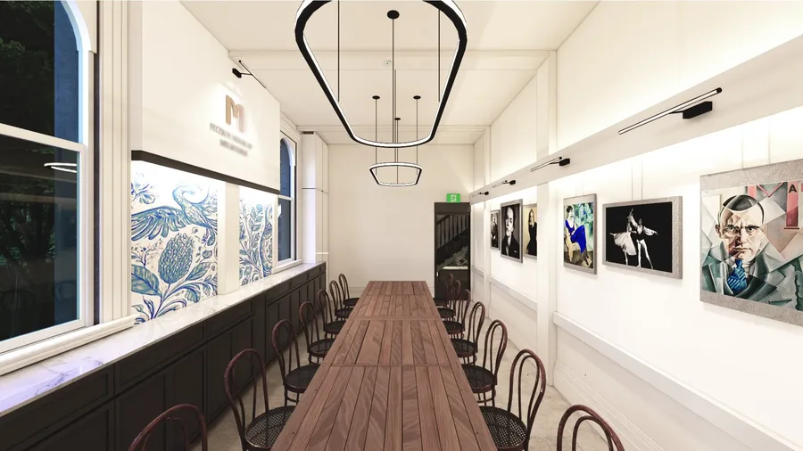 Long communal dining table with bentwood chairs beneath ring pendant lights, gallery artwork along the wall