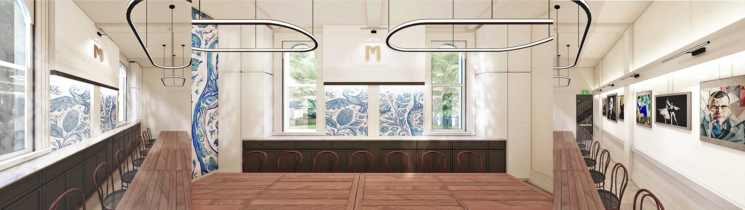 An art gallery with white walls, displaying framed artwork on the right wall, large windows with floral murals, and a wooden table with chairs in the center of the room.
