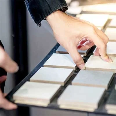 A person selecting tile samples from a display rack
