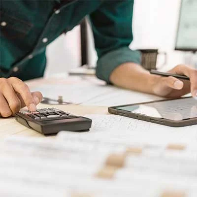 Person using a calculator and a smartphone on a desk with papers.